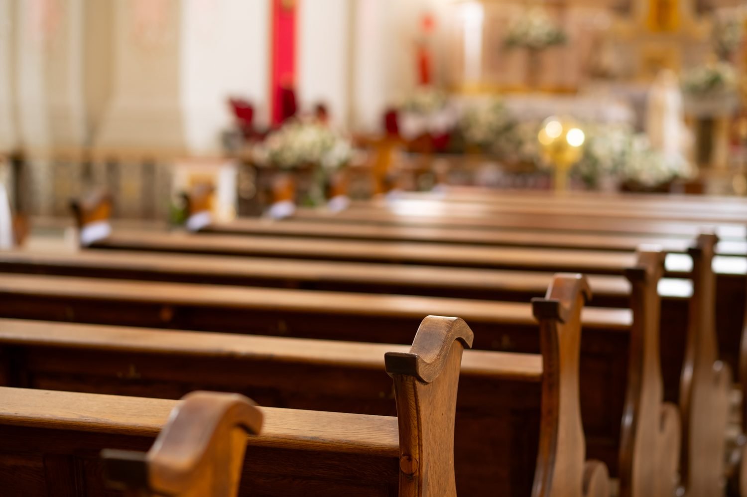 Empty wooden pews before a lit altar